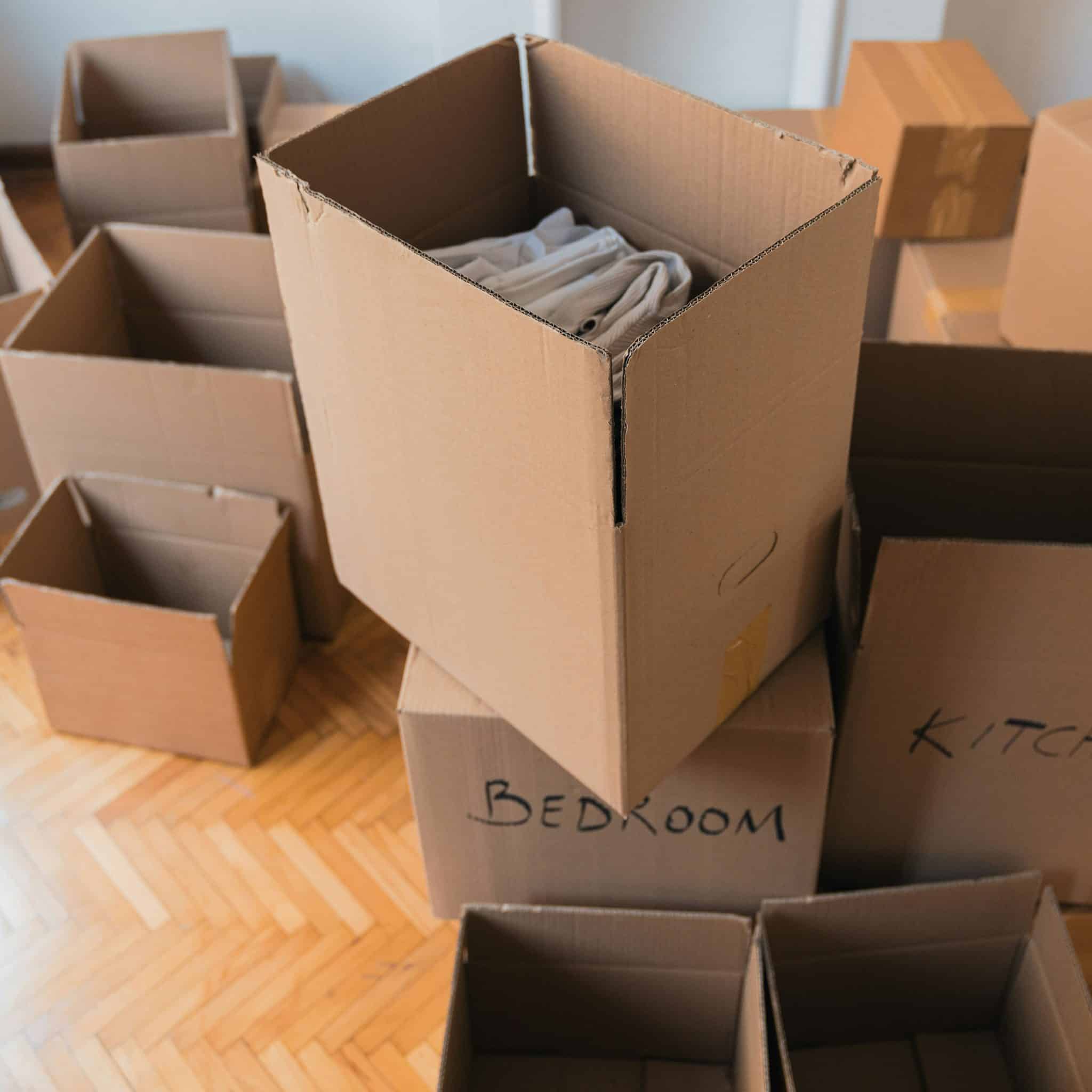 A collection of cardboard moving boxes neatly packed and labeled for different rooms, including bedroom and kitchen. Ideal for home relocation, organization, and packing efficiency. Moving day preparation with sturdy storage solutions